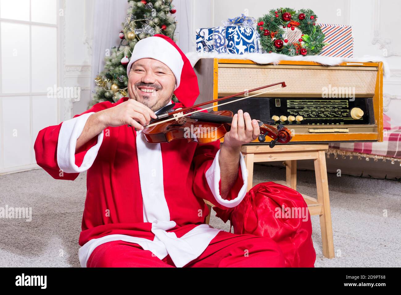 Homme barbu vêtu d'un costume de Père Noël jouant au studio de violons portrait Banque D'Images