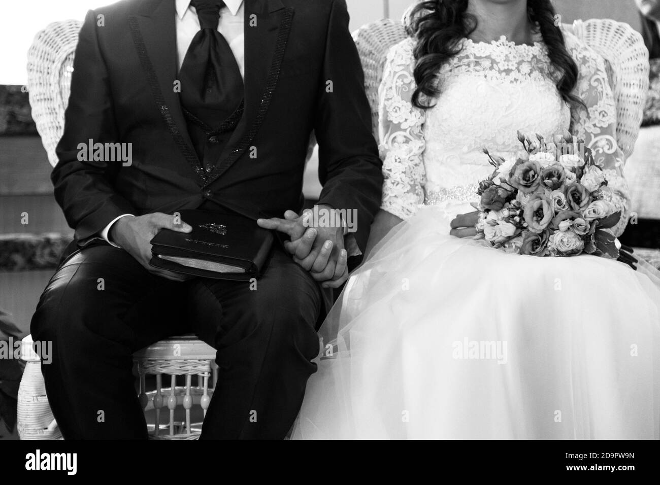 Prise de vue en niveaux de gris d'une mariée et d'un marié tenant les mains au cours de la cérémonie de mariage en niveaux de gris Banque D'Images