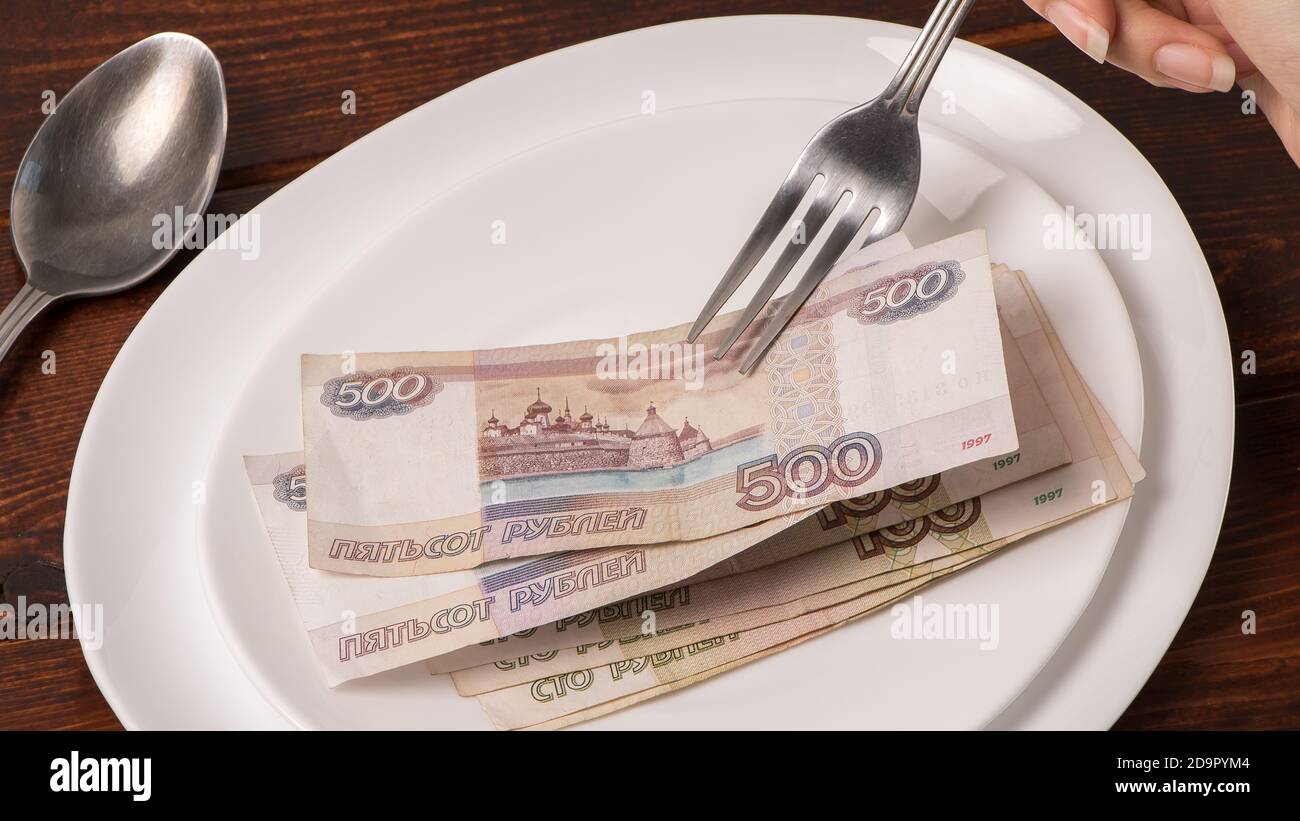 Roubles russes sur une plaque blanche. Gardez de l'argent sur la fourchette. Niveau minimum de subsistance, panier de nourriture, salaire minimum. Concept. Manger de l'argent, vivre salaire. Econom Banque D'Images