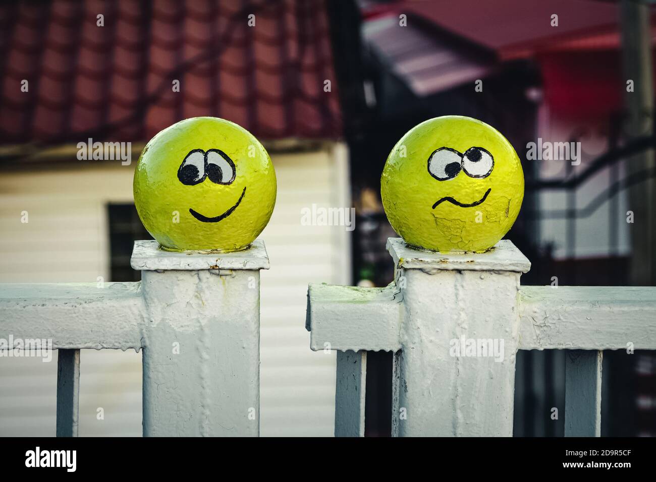 Deux smileys jaunes, drôles et fous, décorent une clôture blanche en métal. Banque D'Images Deux smileys jaunes, drôles et fous, décorent une clôture blanche en métal. Banque D'Images