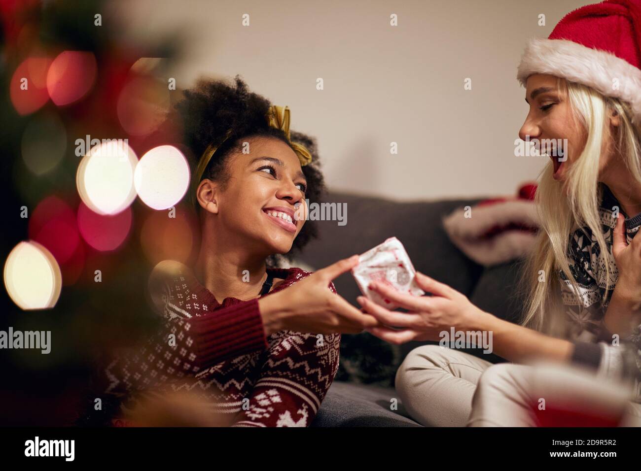 Deux amies échangeant des cadeaux de Noël ensemble ; concept de célébration de Noël à domicile Banque D'Images