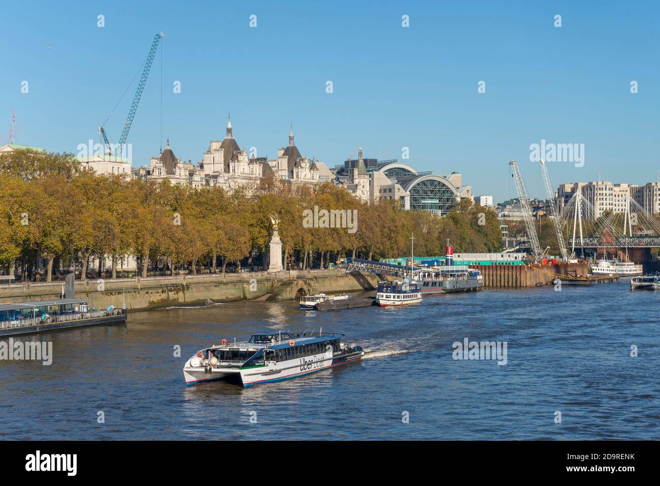 Bateau Uber sur la Tamise, Londres, Royaume-Uni. Venus Clipper approche de Westminster Millennium Pier par le Victoria Embankment avec des arbres d'automne Banque D'Images