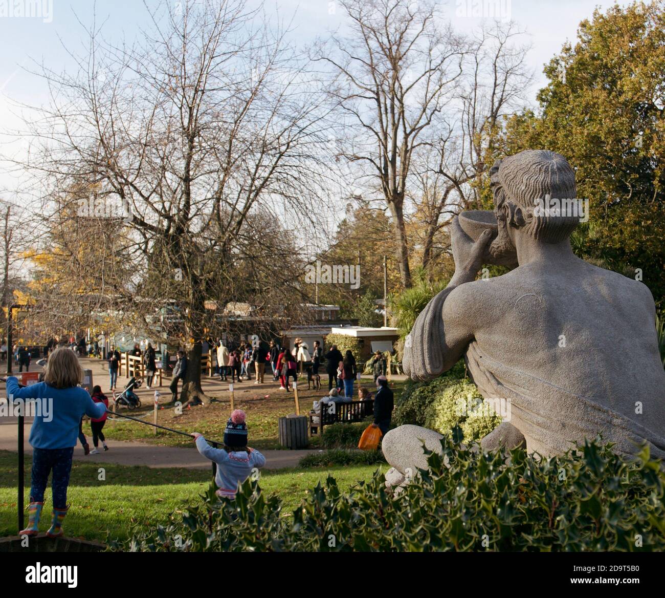 La sculpture de Mark Batten « le Diogeniste ». Une statue donnant sur un parc bondé de Golders Hill avec des enfants jouant en premier plan. Banque D'Images