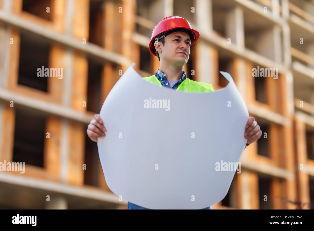 Gros plan des ingénieurs travaillant sur un chantier de construction tenant un modèles Banque D'Images