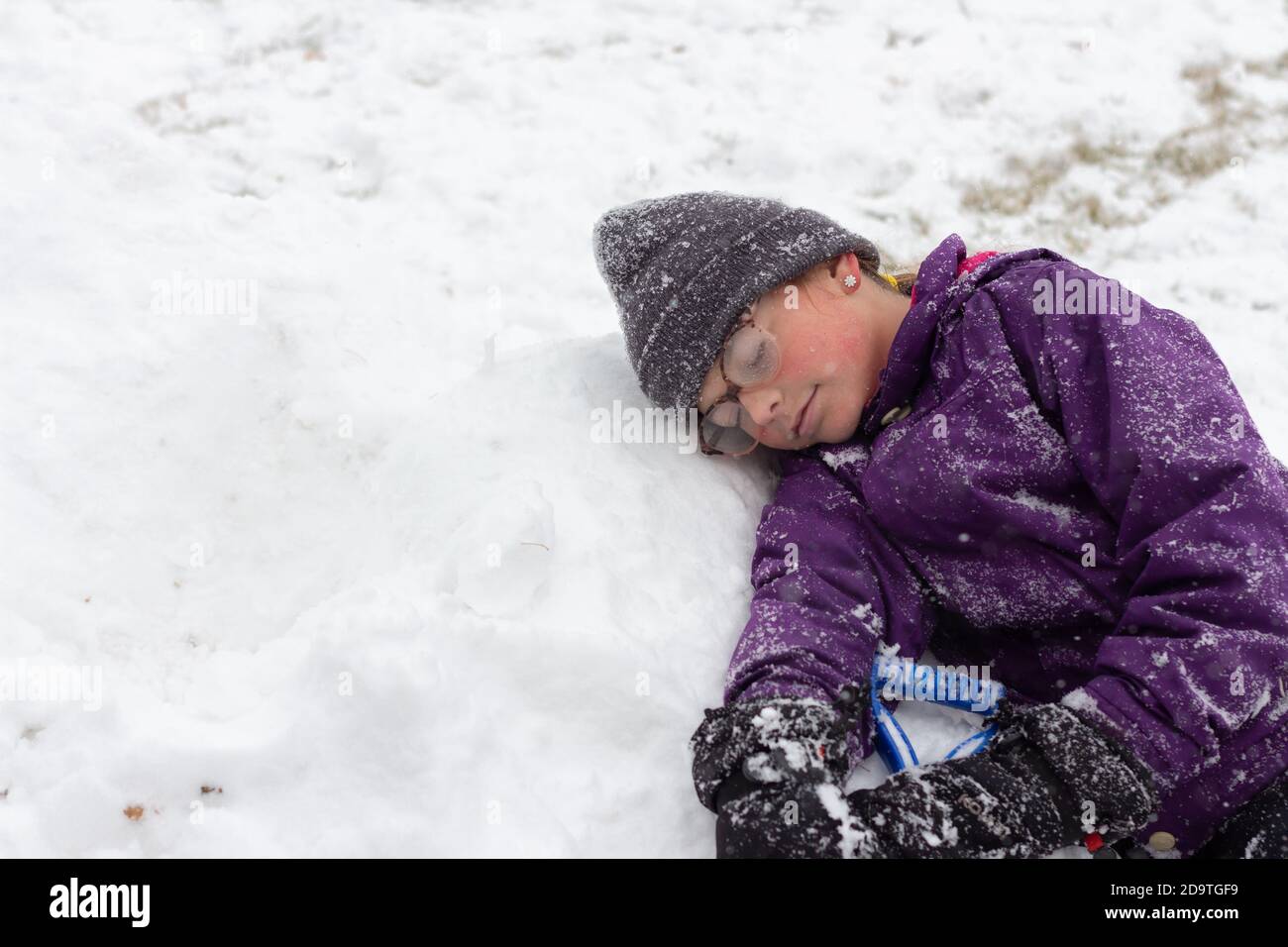 Enfant se reposant dans la neige en appréciant être dehors pendant la chute de neige Banque D'Images