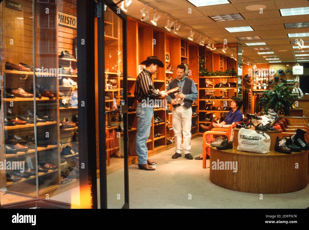 Cowboy à la recherche d'une nouvelle paire de bottes tandis que sa femme regarde, New York City, USA Banque D'Images Cowboy à la recherche d'une nouvelle paire de bottes tandis que sa femme regarde, New York City, USA Banque D'Images