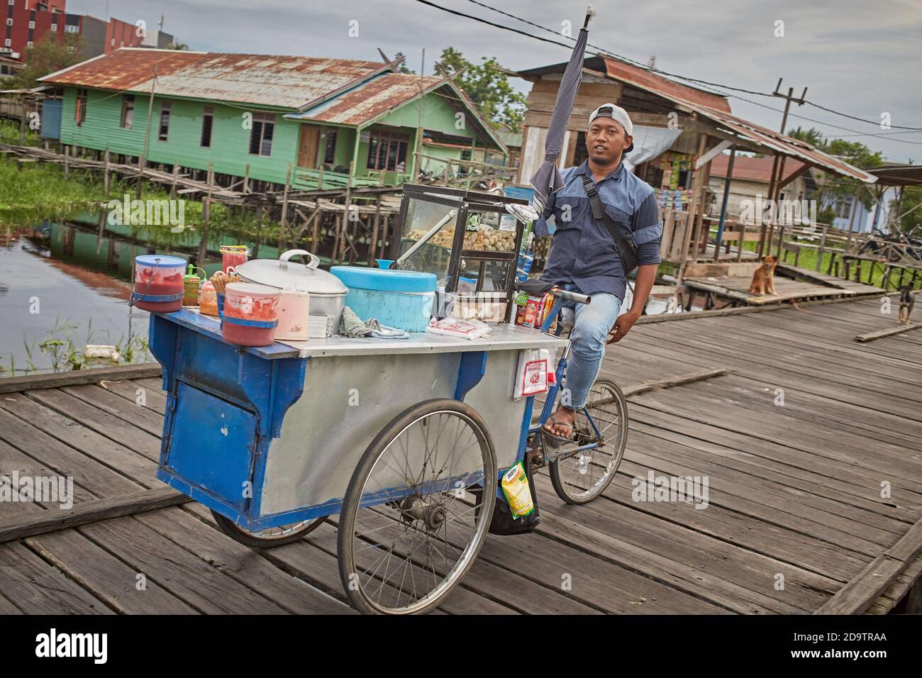 Palangka Raya, Kalimantan, Indonésie, février 2016. Un pédalier avec son tricycle traverse un quai de la ville. Banque D'Images