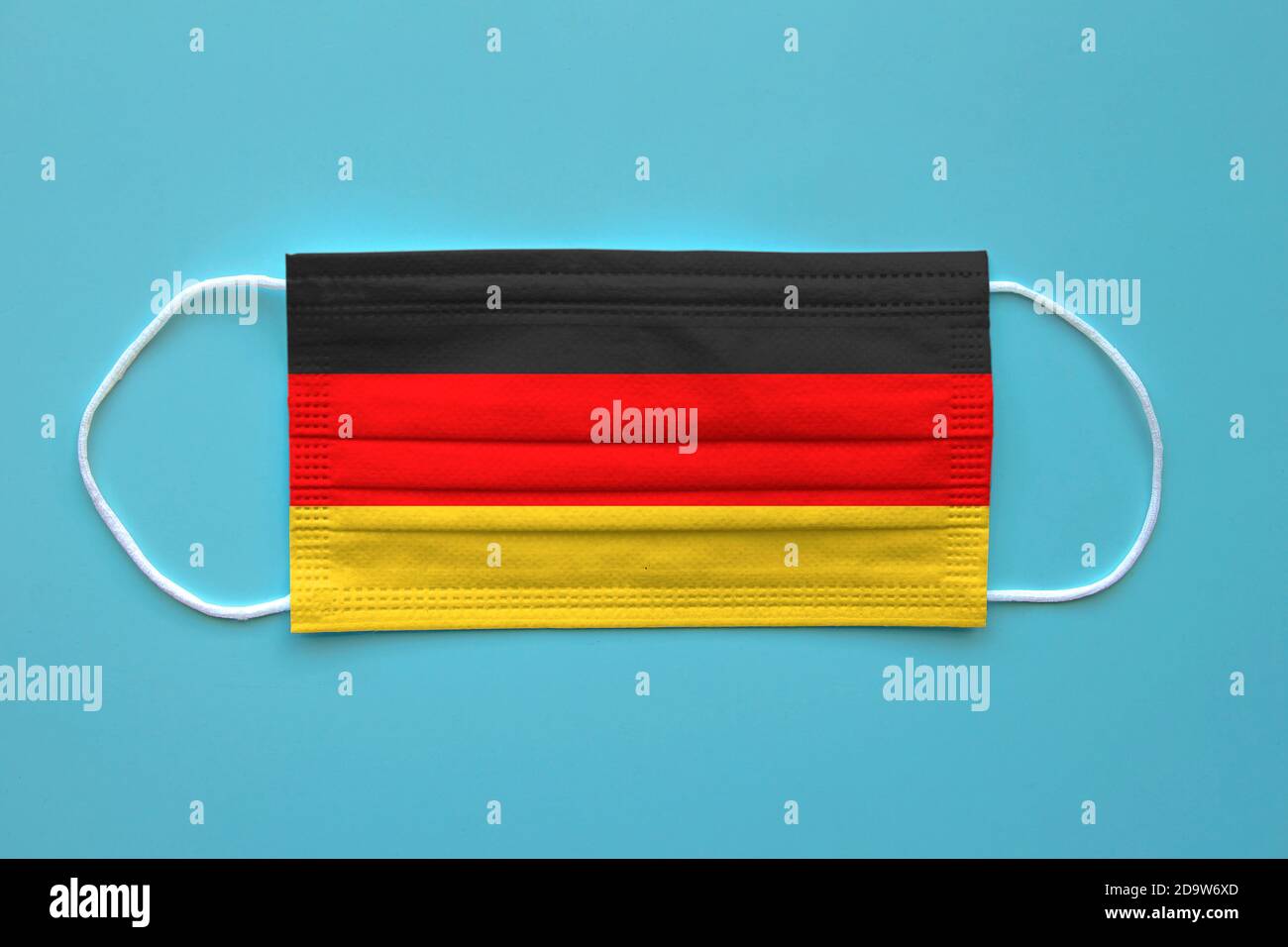Un masque facial avec un drapeau allemand sur un fond clair. Concept: Allemagne pendant la pandémie. Banque D'Images