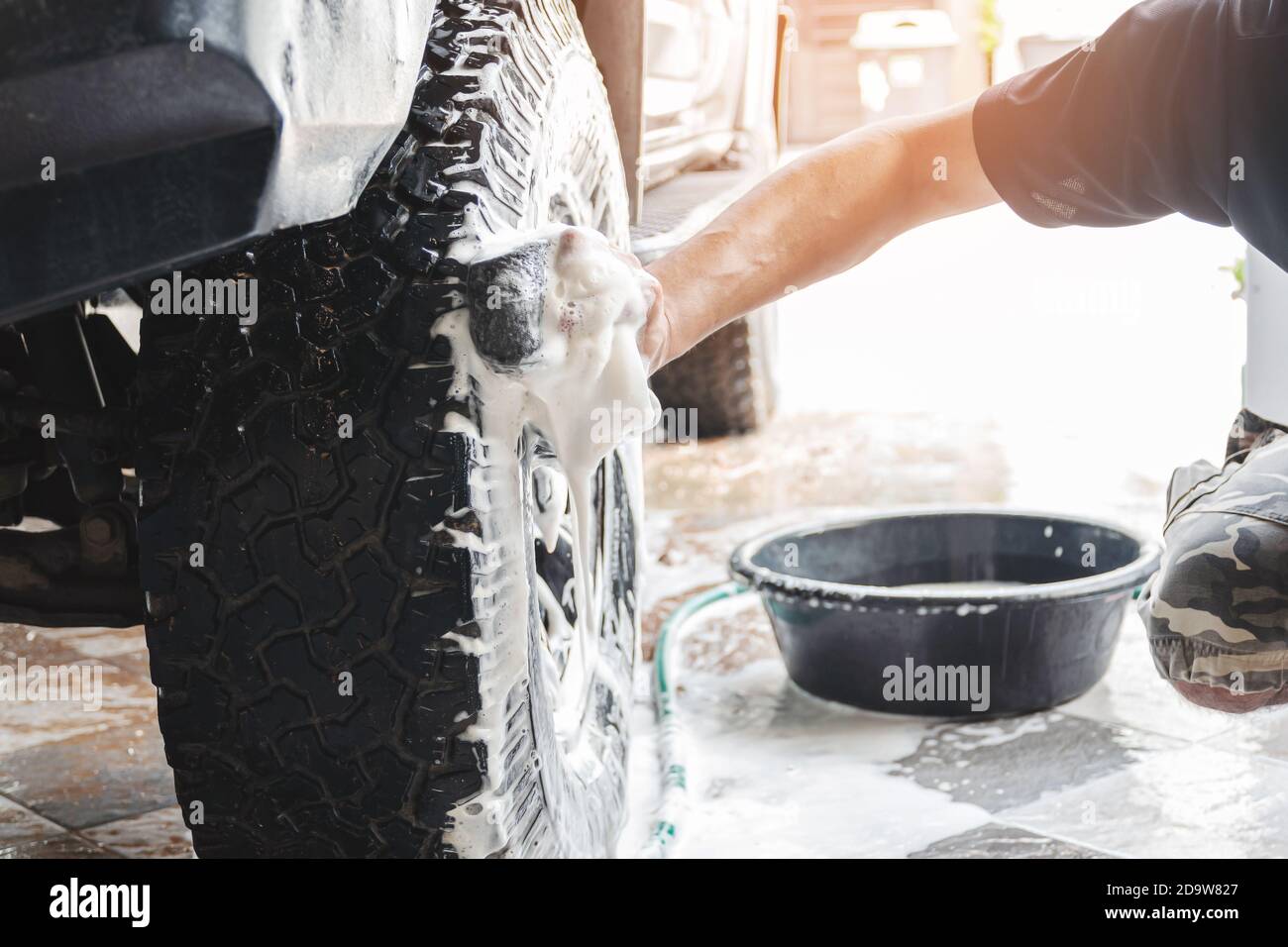 Le personnel de lavage de voiture utilise une éponge humidifiée avec du savon et de l'eau pour nettoyer les roues de la voiture. Banque D'Images
