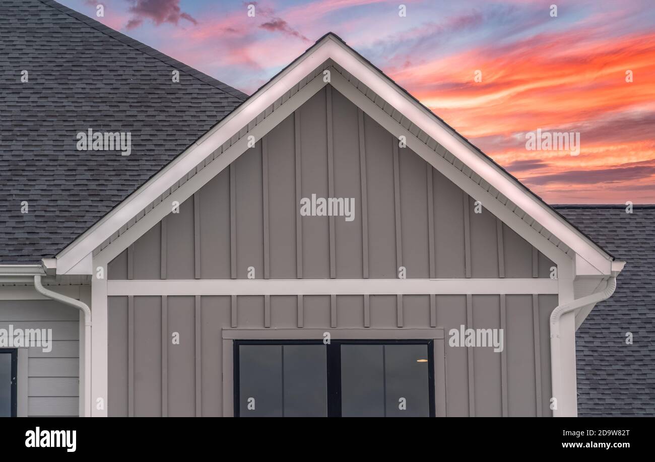 Système de protection de gouttière à cadre blanc, avec parement en vinyle gris foncé, accents blancs, fascia, soffit, sur un toit incliné grenier d'un américain de luxe Banque D'Images