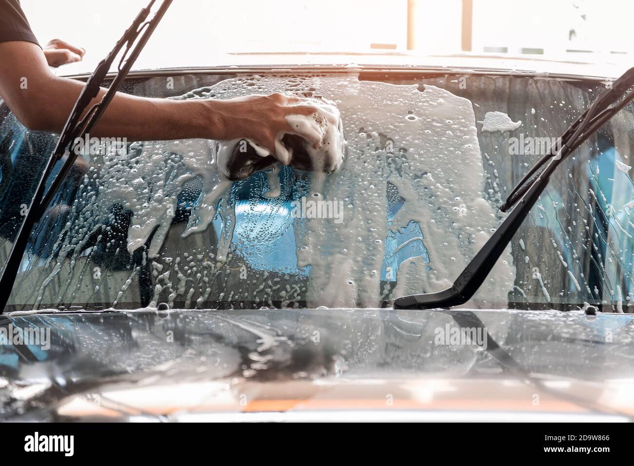 Le personnel de lavage de voiture utilise une éponge pour nettoyer le pare-brise de la voiture. Banque D'Images