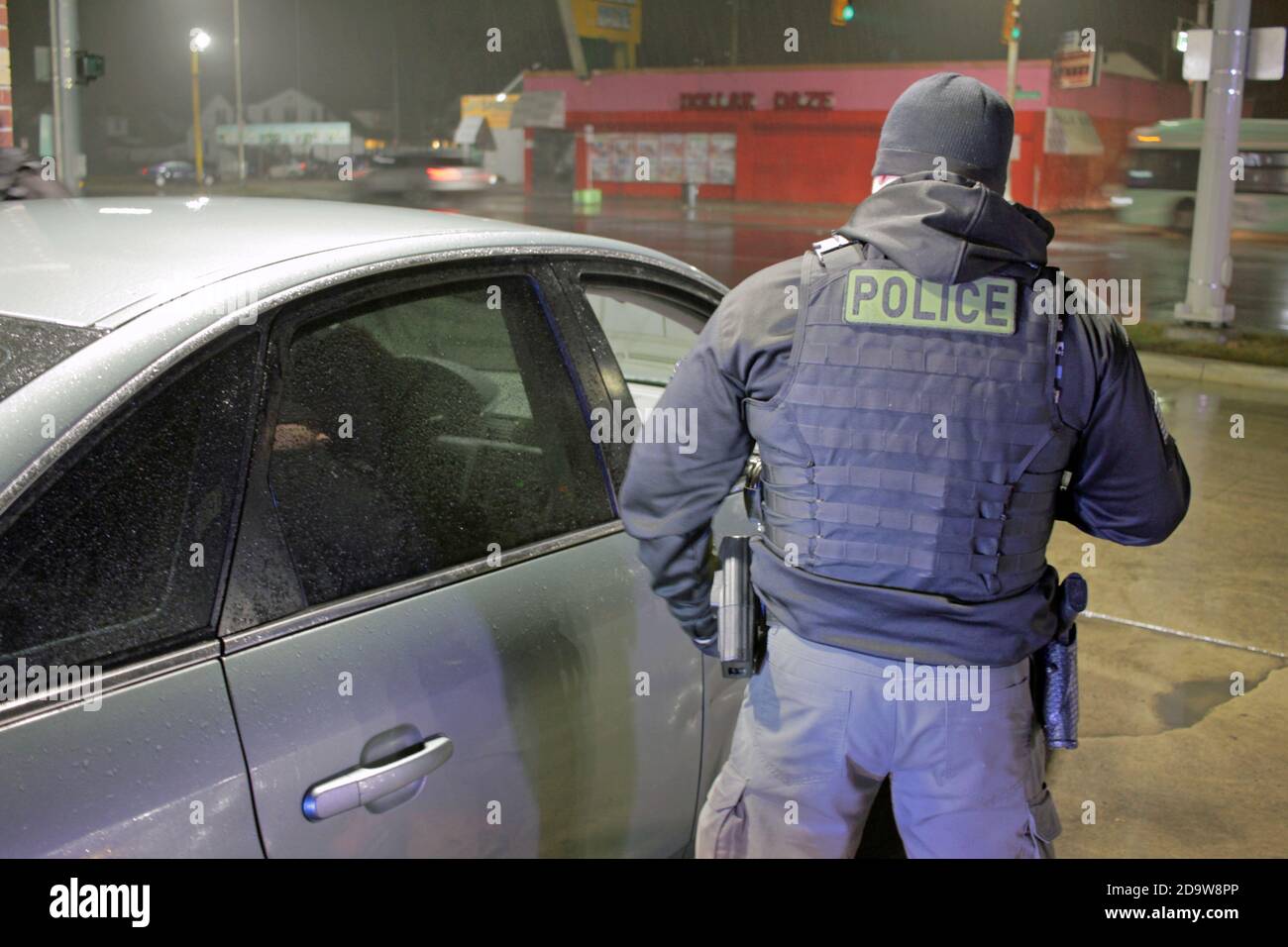 Un agent de police de Detroit évalue une voiture lors d'une nuit de pluie à Detroit, Michigan, États-Unis Banque D'Images