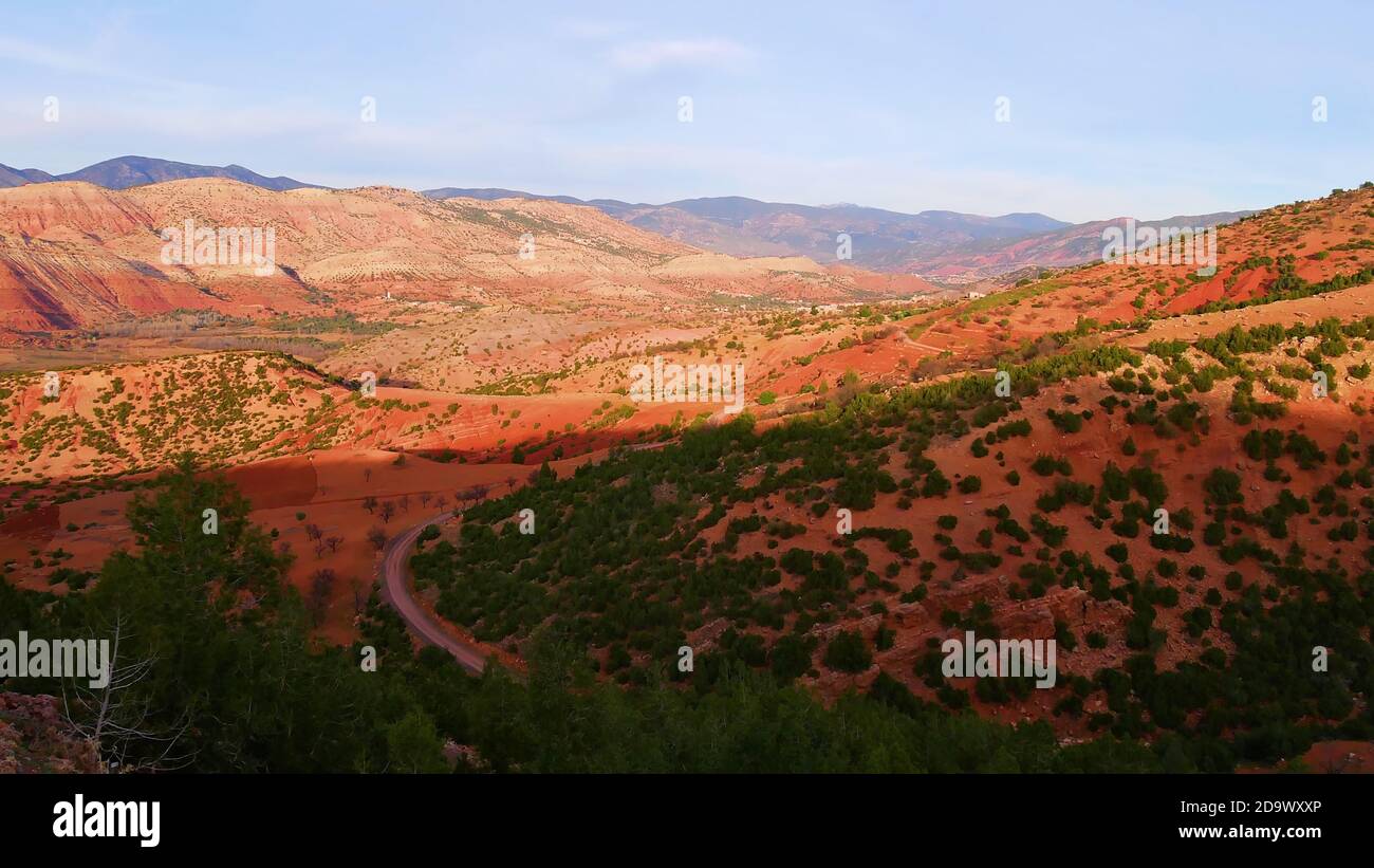 Belle vue panoramique sur les contreforts rouges des montagnes de l'Atlas près d'Ouzoud, Maroc, Afrique avec route et forêt dans la lumière du soir. Banque D'Images