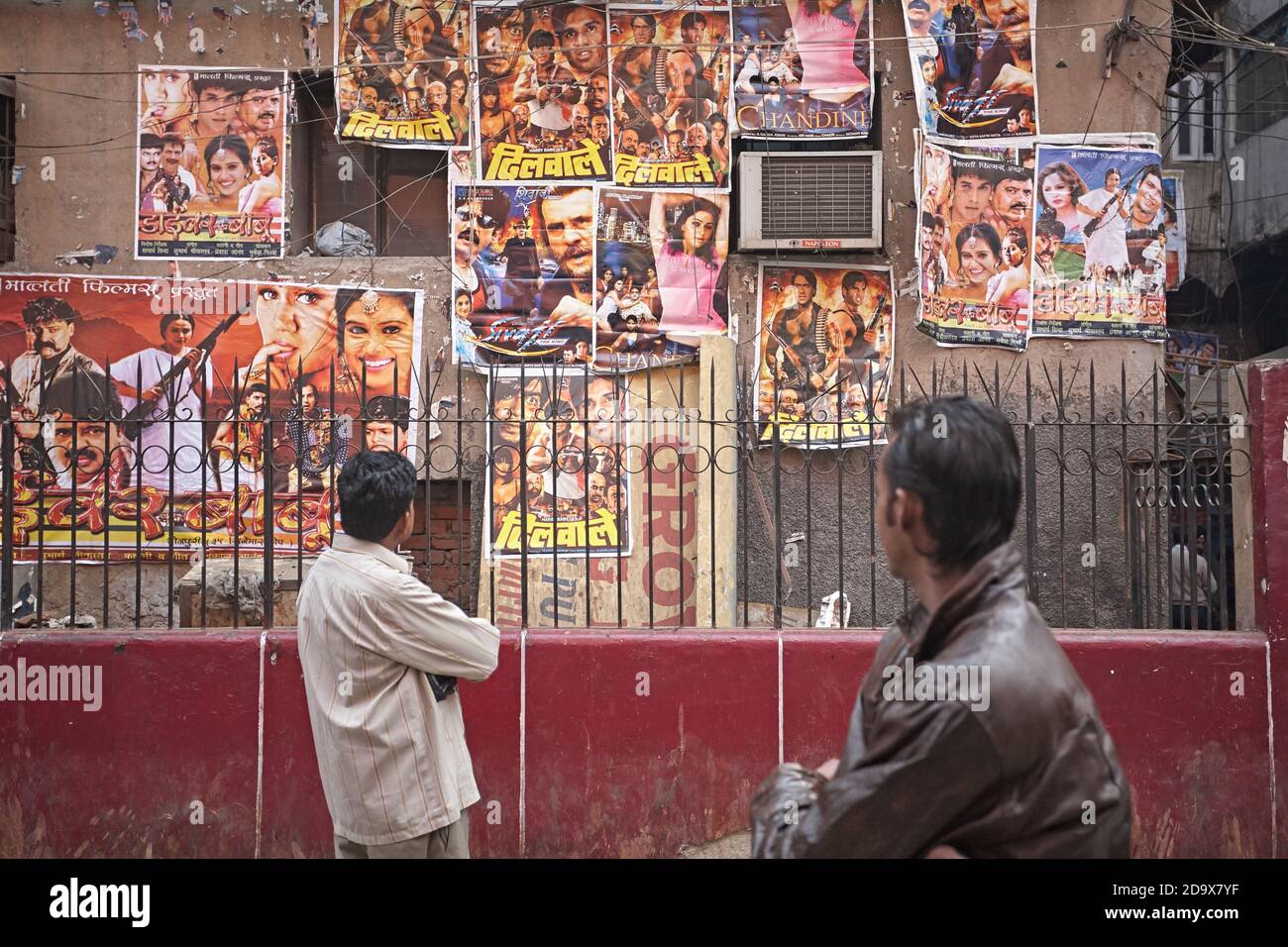 Delhi, Inde, janvier 2008. Deux hommes regardent des affiches de film de Bollywood attachées au mur. Banque D'Images