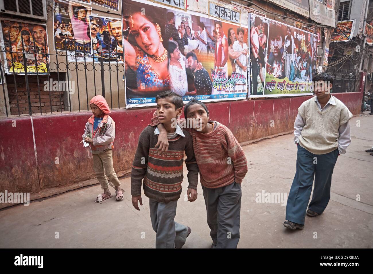 Delhi, Inde, janvier 2008. Errant les enfants devant les affiches de film de Bollywood attachées au mur. Banque D'Images