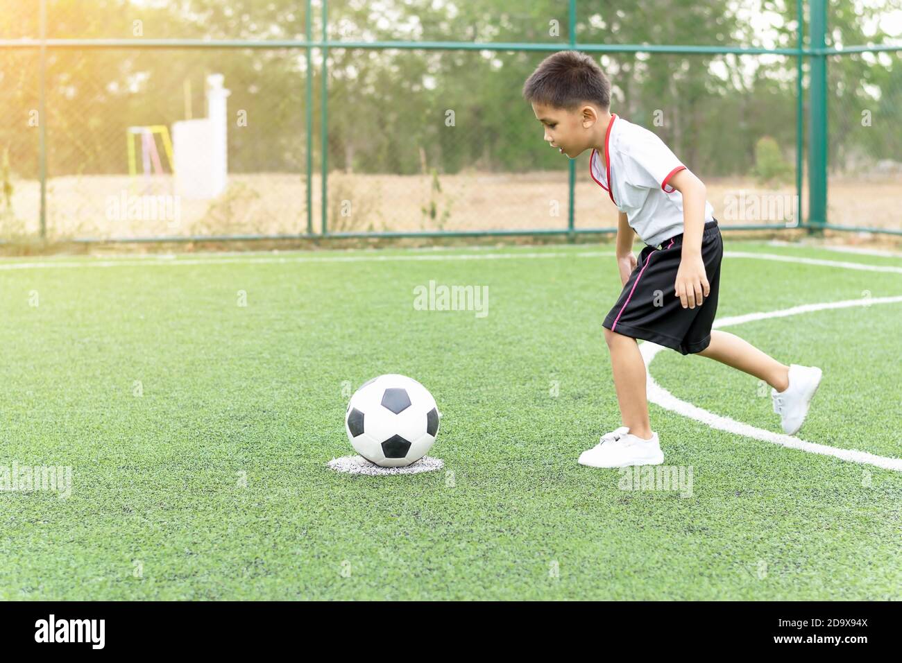 Le garçon jouait au football sur le terrain de football avec bonheur. Banque D'Images
