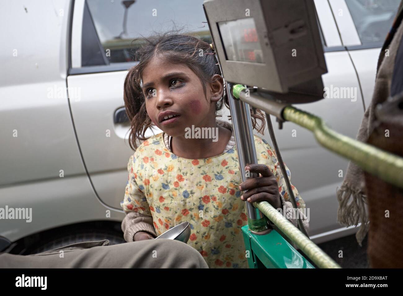 Delhi, Inde, janvier 2008. Une pauvre fille supplie les occupants d'un pousse-pousse au milieu de la circulation. Banque D'Images