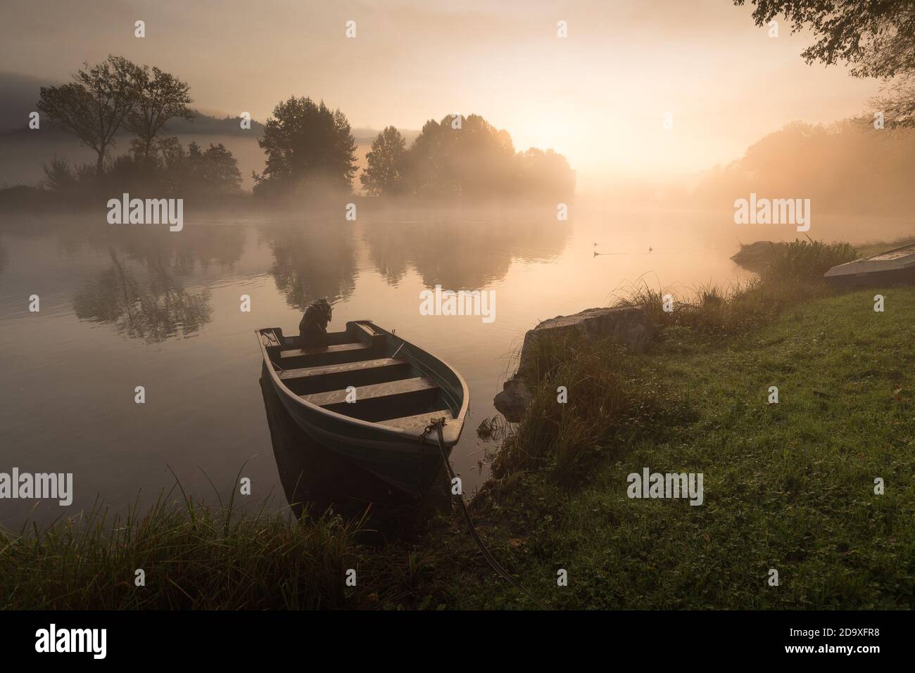 Calme pittoresque photo de petit bateau de pêche sur l'Adda rivière sur un lever de soleil brumeux avec feuillage Banque D'Images