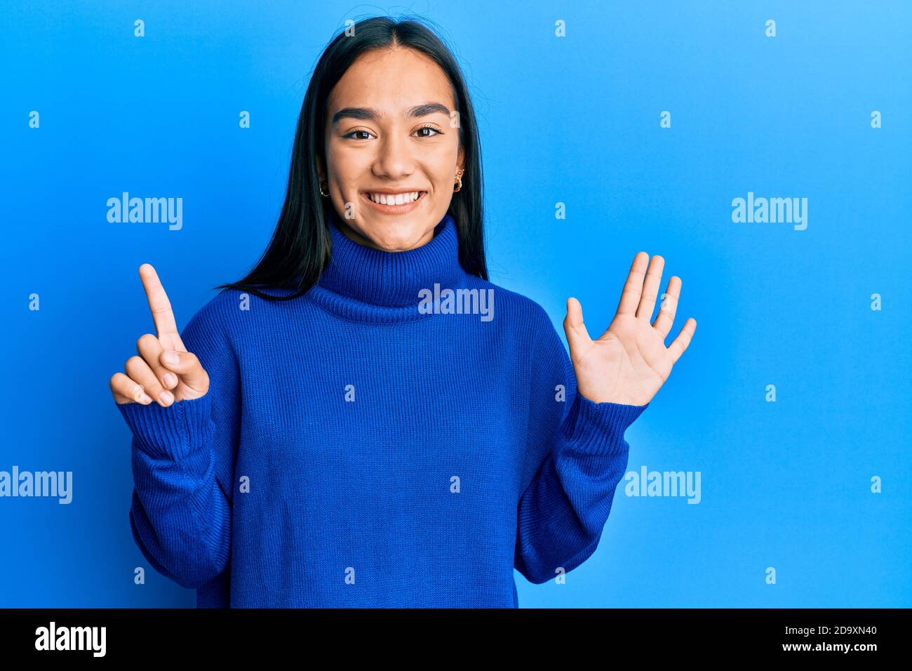 Jeune femme asiatique portant un chandail d'hiver décontracté montrant et pointant vers le haut avec les doigts numéro six tout en souriant confiant et heureux. Banque D'Images