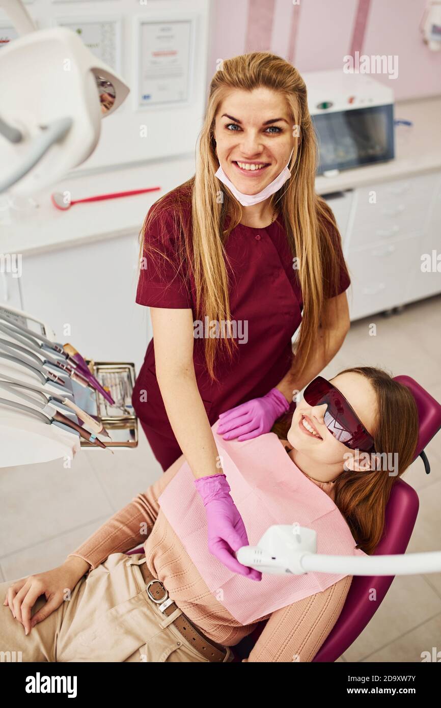 Petite fille en lunettes de protection rendant visite à un dentiste en clinique. Conception de la stomatologie Banque D'Images