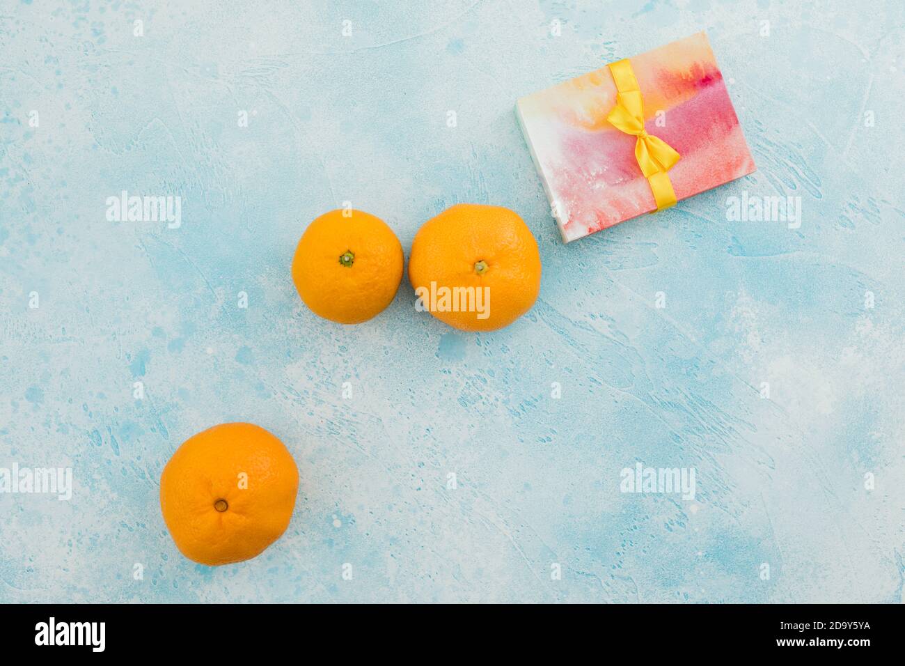 Fruits mandarins avec boîte cadeau et fond bleu. Pose à plat Banque D'Images