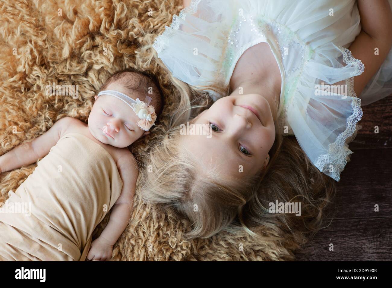 Petite fille de race blanche et sa sœur de nouveau-né. Jeune enfant  rencontre un nouveau frère ou une sœur. Une jolie fille et un nouveau-né se  détendent dans une chambre à coucher.