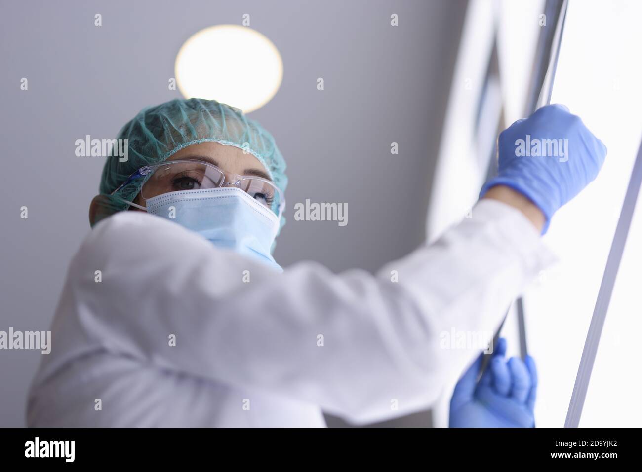 Médecin en lunettes et masque médical et gants tient une image radiologique. Banque D'Images
