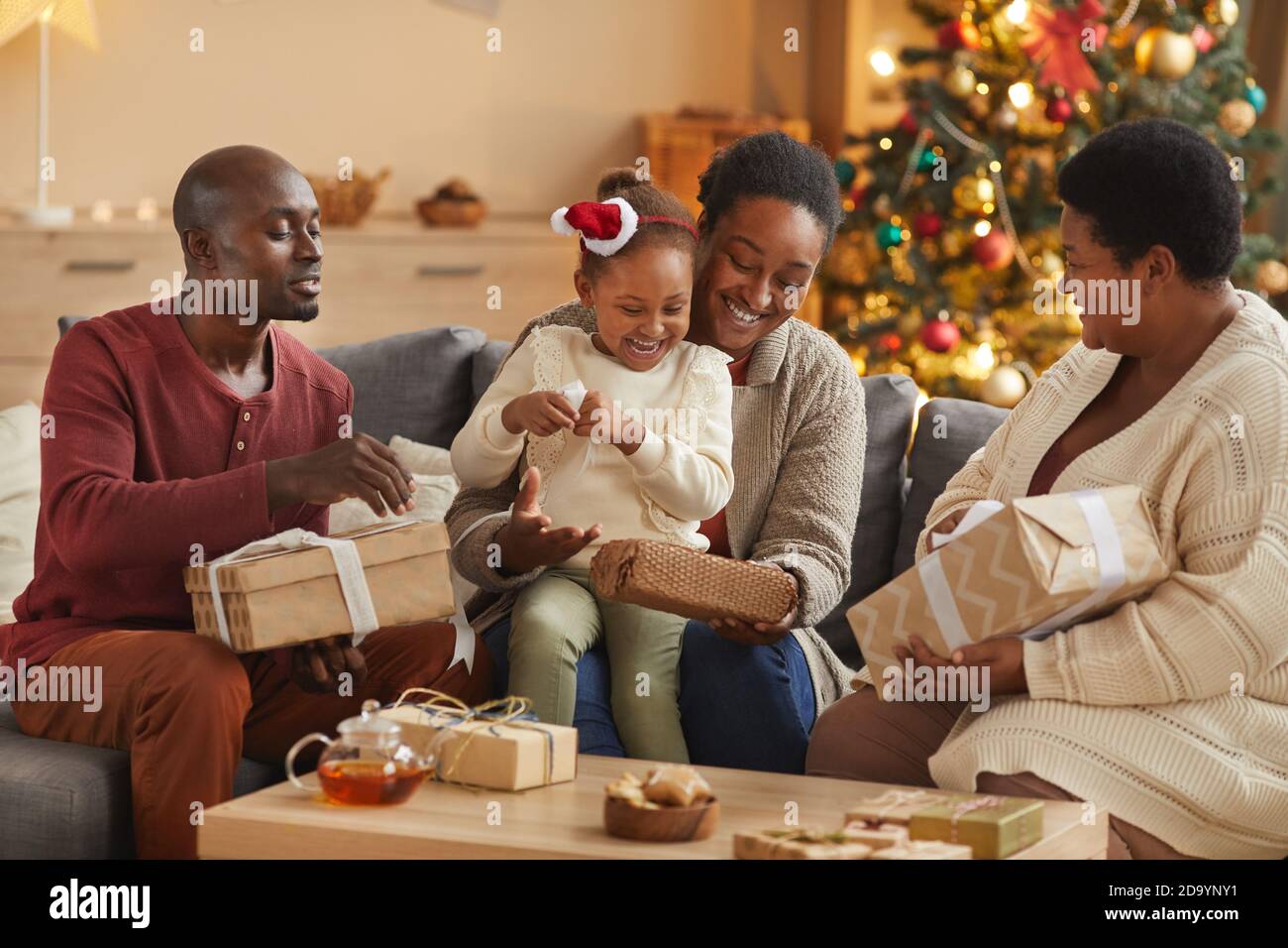 Portrait aux tons chaleureux d'une famille afro-américaine heureuse ouvrant des cadeaux de Noël pendant profitez des vacances à la maison Banque D'Images