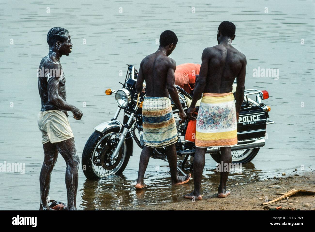 Moto de police lavée et les hommes se lavant sur le rive du fleuve Milo affluent du Niger Rivière Kankan Guinée Afrique de l'Ouest 1979 Banque D'Images