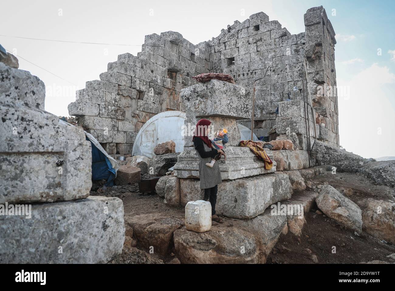 Babisqa, Syrie. 07th nov. 2020. Une jeune femme tient un bébé au milieu des restes d'une ancienne église dans le village de Babisqa. Environ 6 familles syriennes déplacées, dont les maisons dans le village d'Ain la Rose ont été détruites par les bombardements du gouvernement syrien, prennent refuge dans les anciennes églises de Babisqa, qui font partie du site classé au patrimoine mondial de l'UNESCO des villes mortes qui remontent aux époques romaine et byzantine. Credit: Aras Alkharboutli/dpa/Alamy Live News Banque D'Images