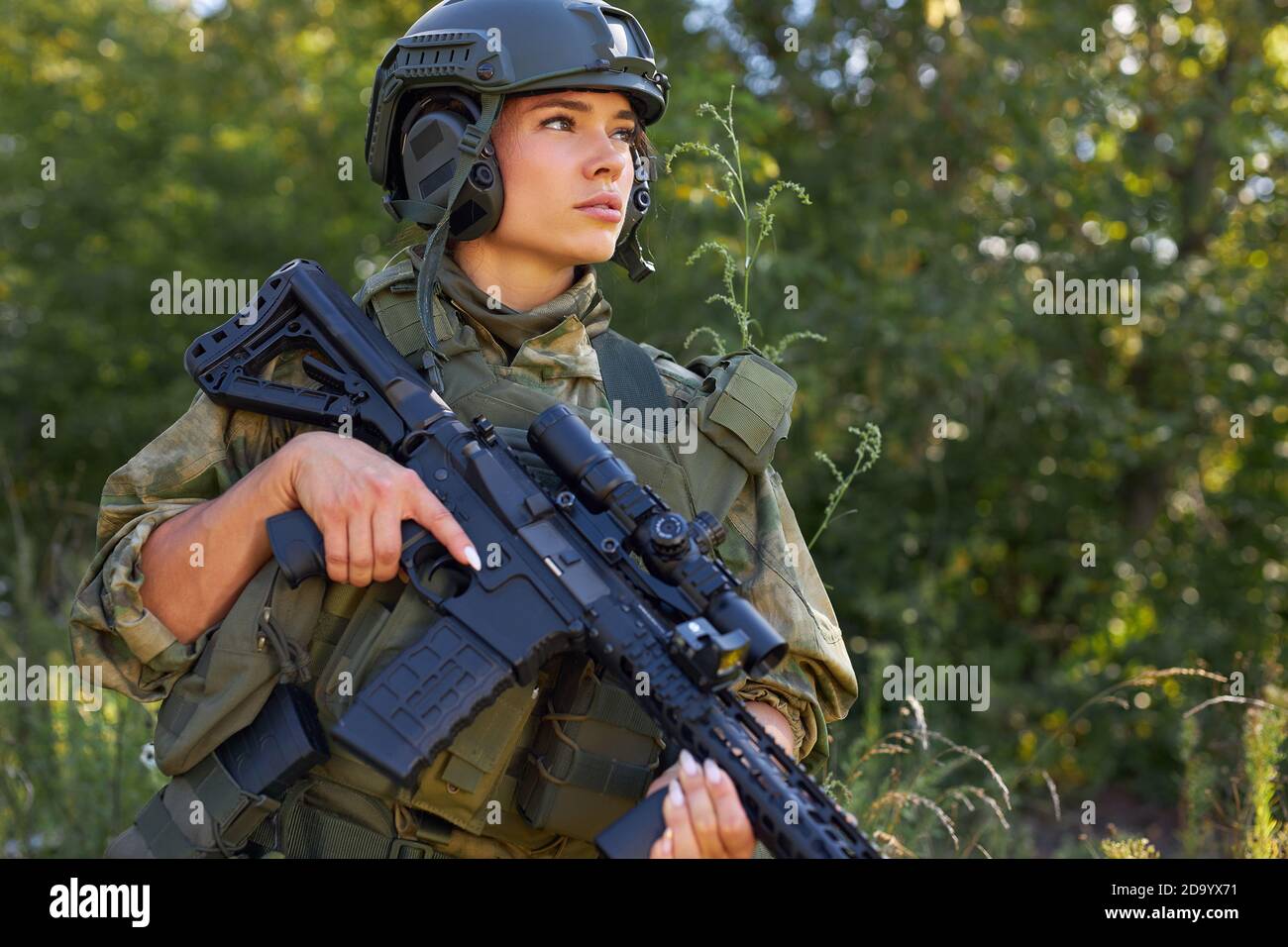 jeune femme militaire caucasienne tient une arme dans sa main dans la nature, elle va chasser, la chasse en forêt est un passe-temps. jeu avec des armes Banque D'Images