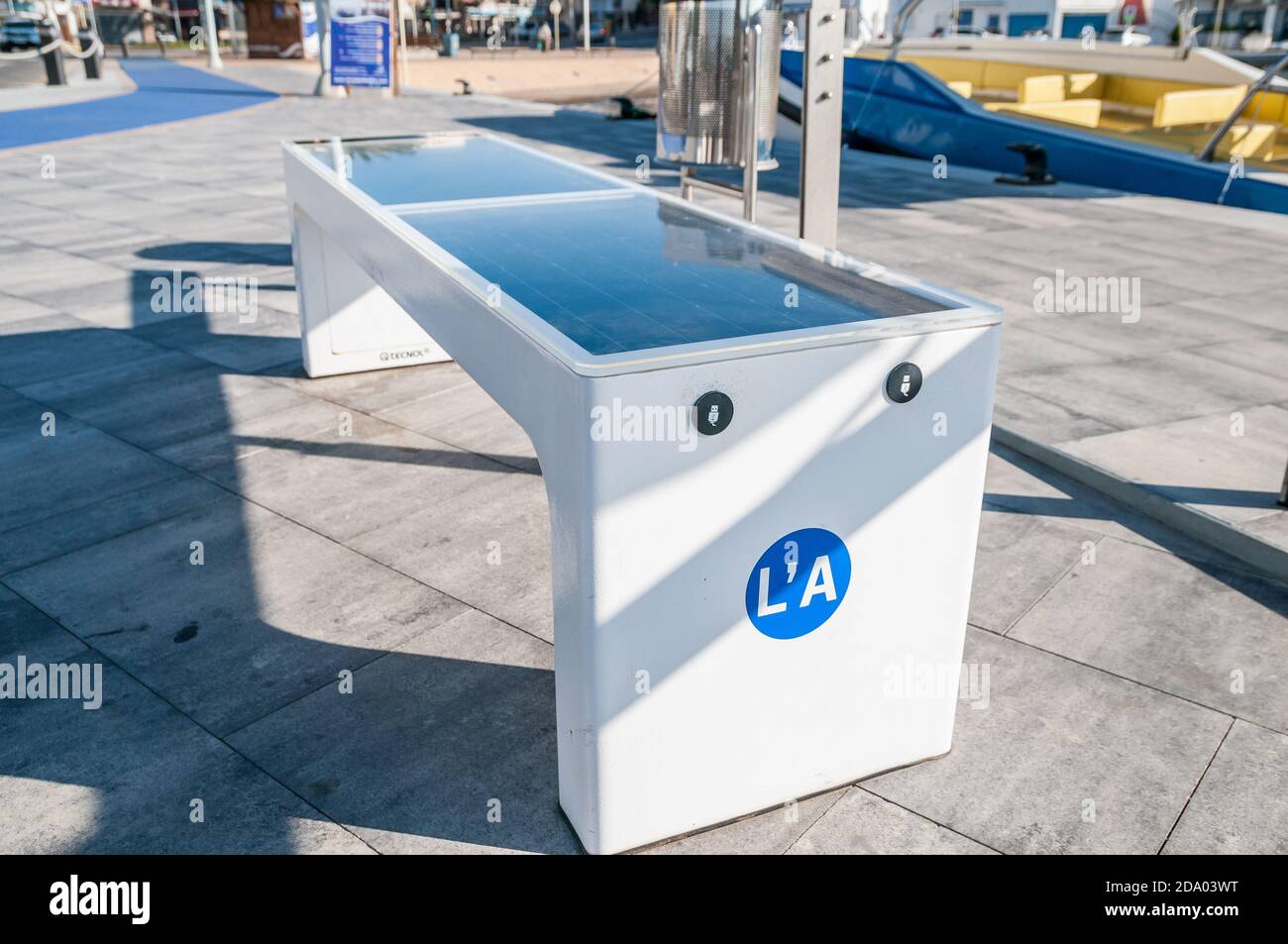 Banc avec panneau solaire et chargeur mobile au bord de l'eau à la Ampolla, Tarragone, Catalogne, Espagne Banque D'Images