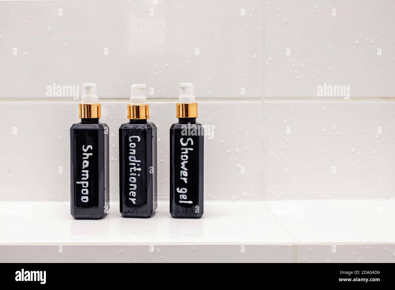 Trois bouteilles avec articles de toilette sur carrelage blanc Banque D'Images
