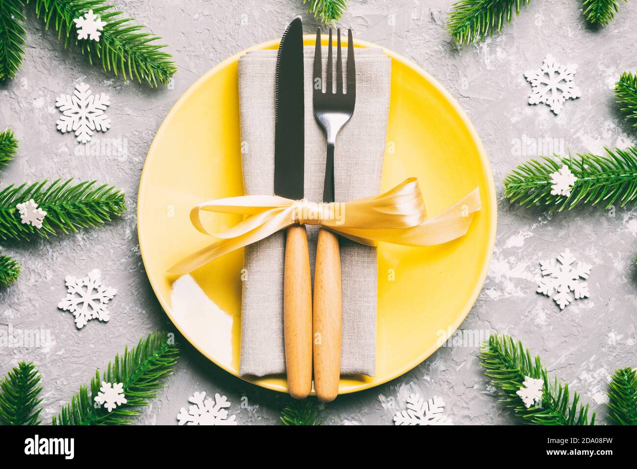 Vue de dessus de nouvelle année le dîner de fête sur fond de ciment. Composition de l'assiette, fourchette, couteau, sapin et de décorations. Joyeux Noël concept. Banque D'Images