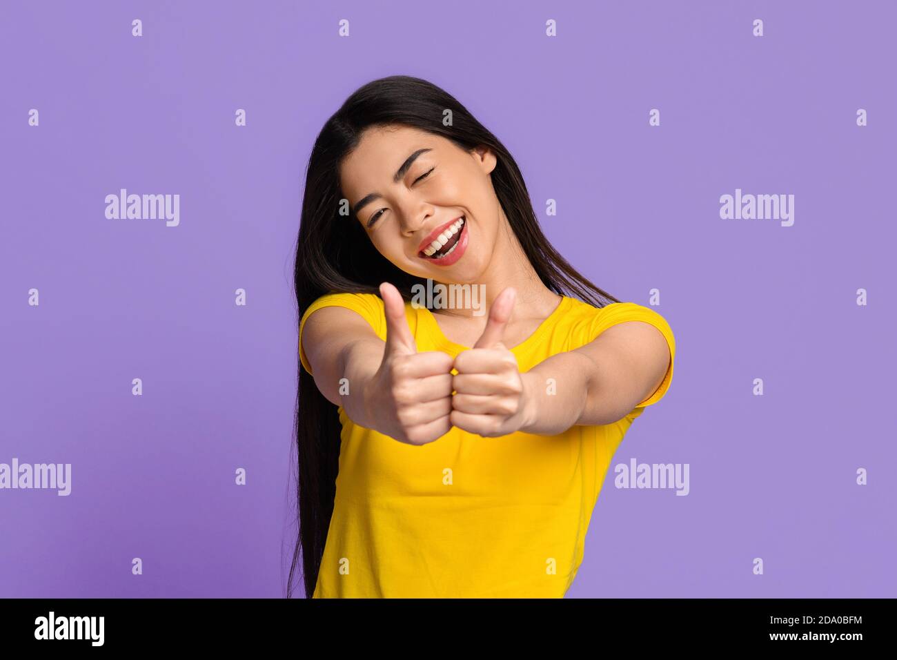 J'aime ça. Joyeuse jeune femme asiatique montrant des Thumbs vers le haut à la caméra Banque D'Images