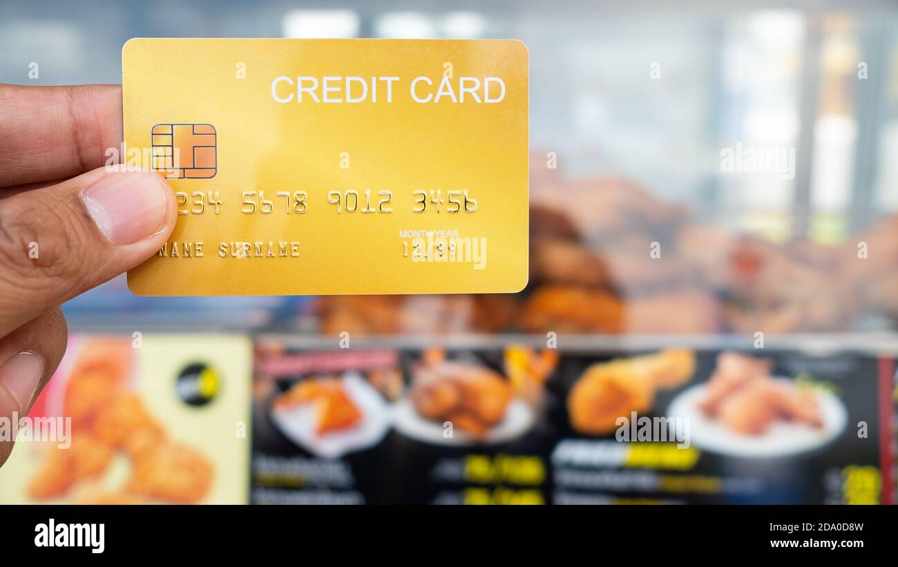 Main tenant la carte de crédit avec le magasin de poulet frit à l'intérieur style background.16:9 Banque D'Images