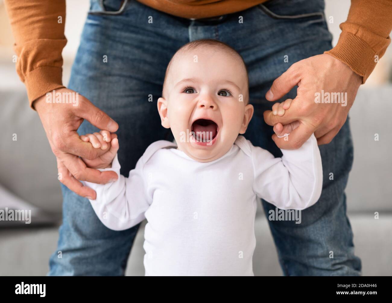 Joyeux petit garçon marchant tenant les mains du Père à la maison Banque D'Images