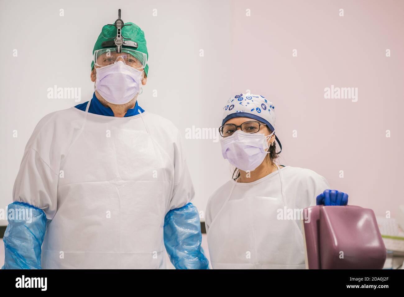 Stomatologue mâle méconnaissable avec collègue femelle dans les masques respiratoires et lunettes de protection regardant la caméra au travail Banque D'Images