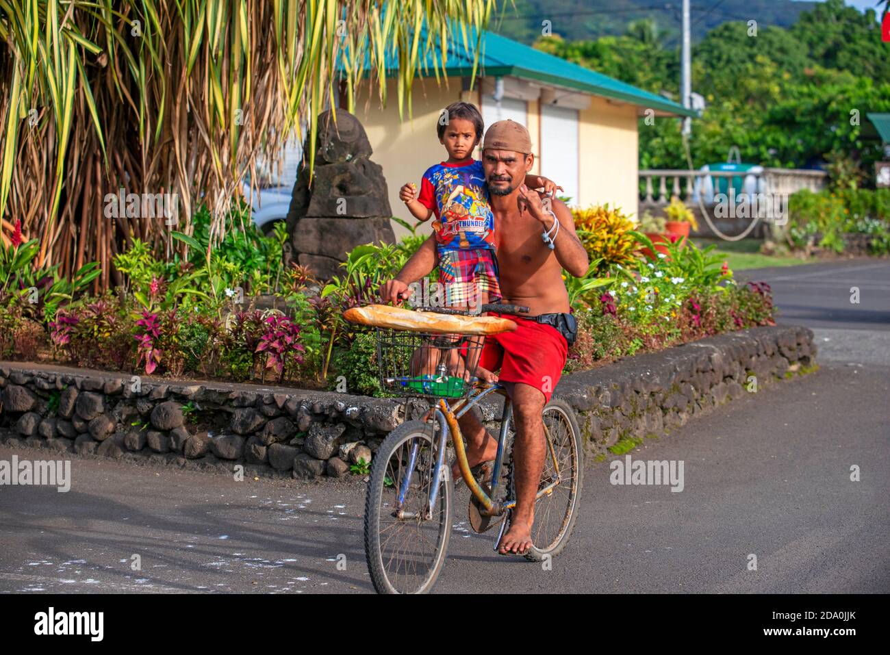 Tahitien homme avec sa fille portant des baguettes tout en faisant un vélo sur l'île de Tahiti, Polynésie française, Tahiti Nui, les îles de la Société, Frenc Banque D'Images