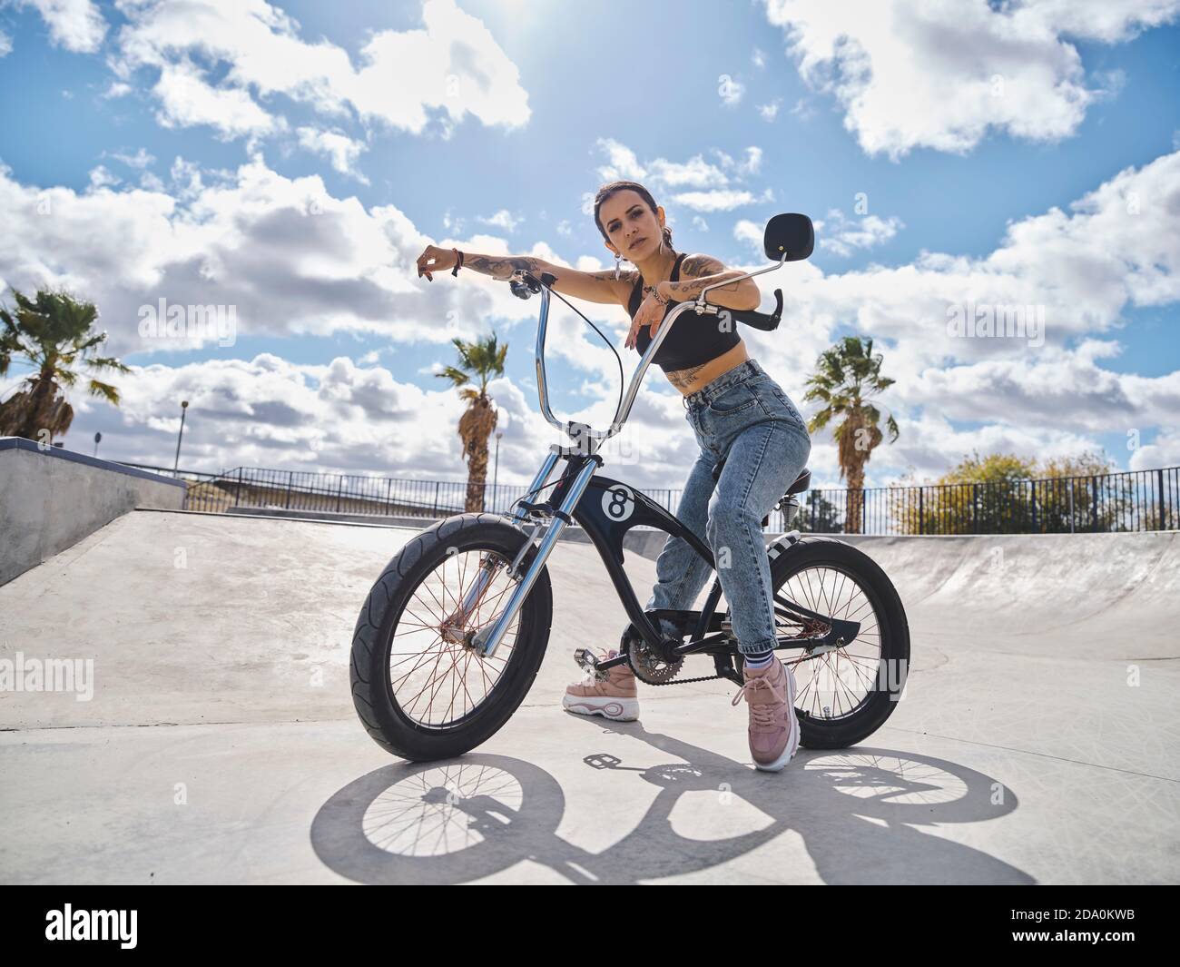 Vue latérale d'une femme tatouée déterminée dans un ensemble élégant assis  Sur le vélo BMX dans le parc de skate et regarder la caméra Photo Stock -  Alamy
