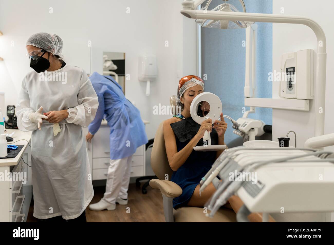Patiente assise sur une chaise et regardant le miroir après recevoir des soins dentaires de dentistes professionnels en clinique moderne Banque D'Images