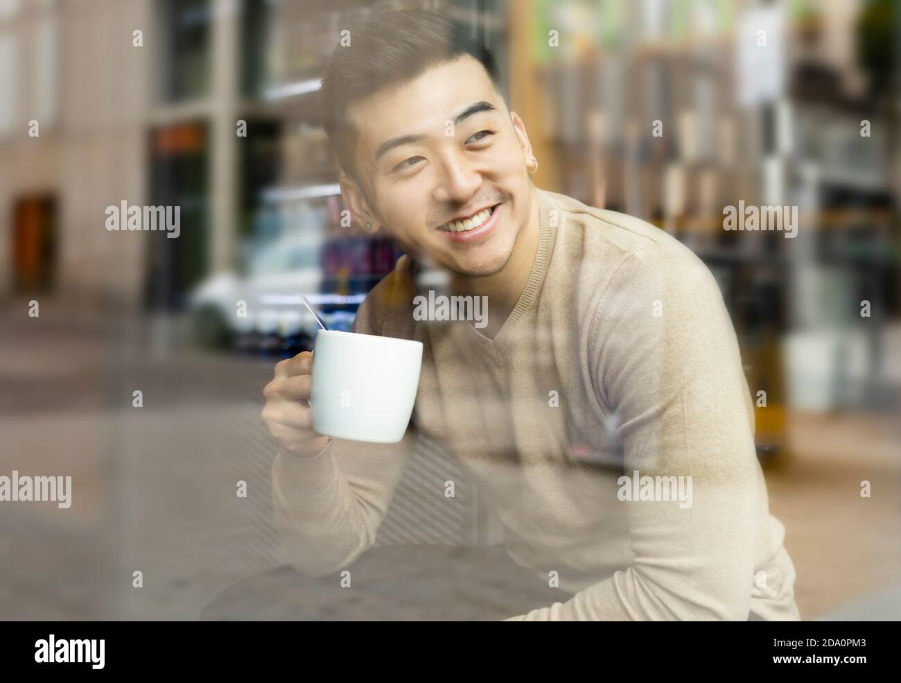 Homme asiatique se détendant dans un fauteuil dans un café confortable et dégustez une boisson chaude tout en regardant loin Banque D'Images