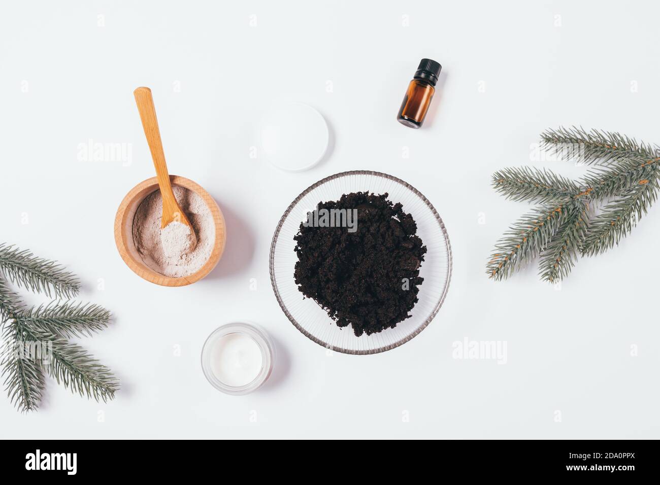 Ingrédients de gommage du corps de café sur la table blanche à côté des branches de sapin, disposition plate de soin de la peau d'hiver. Banque D'Images