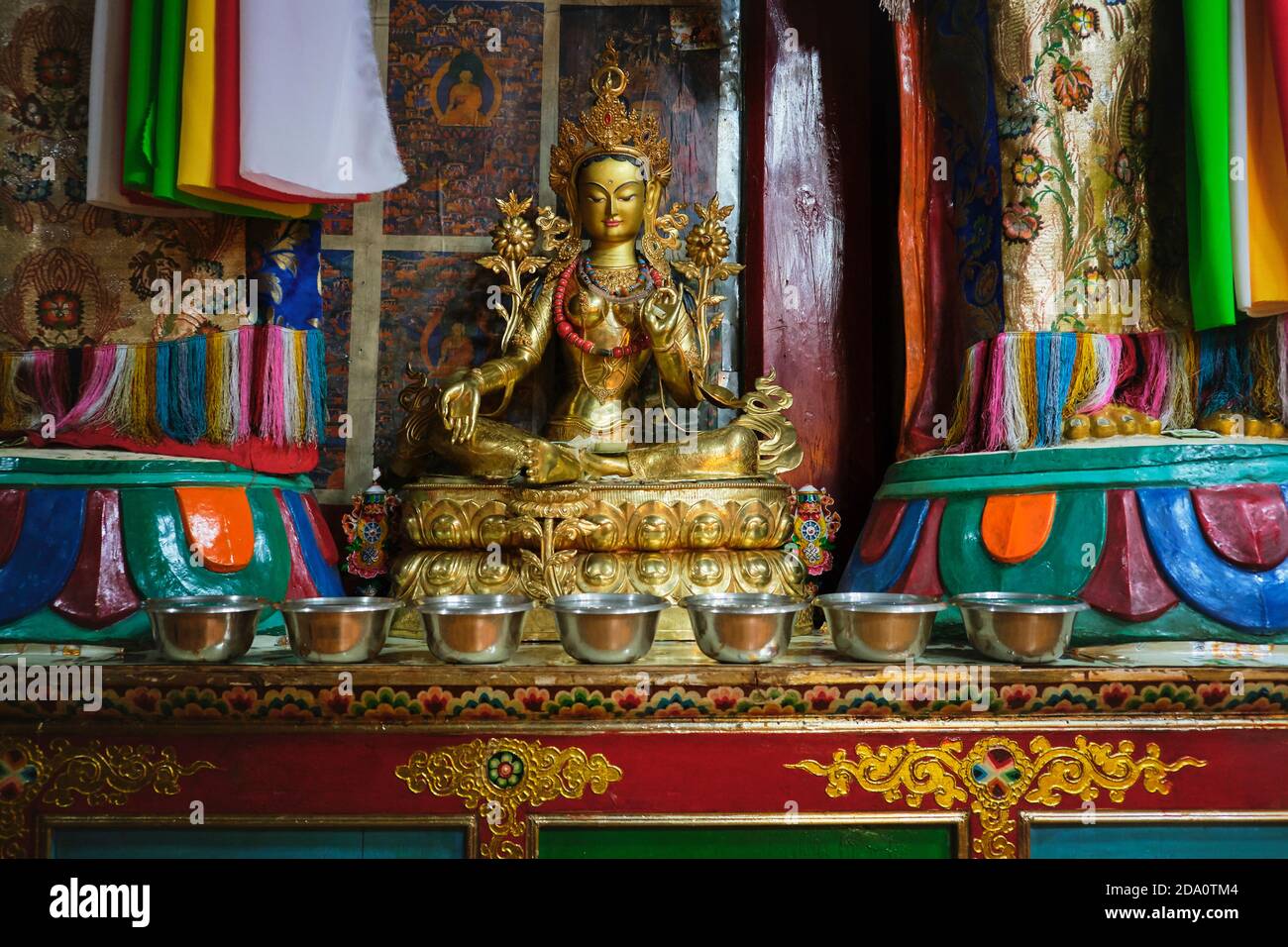 Intérieur du temple oriental traditionnel avec une figurine dorée de prière Bouddha avec bols en métal Banque D'Images