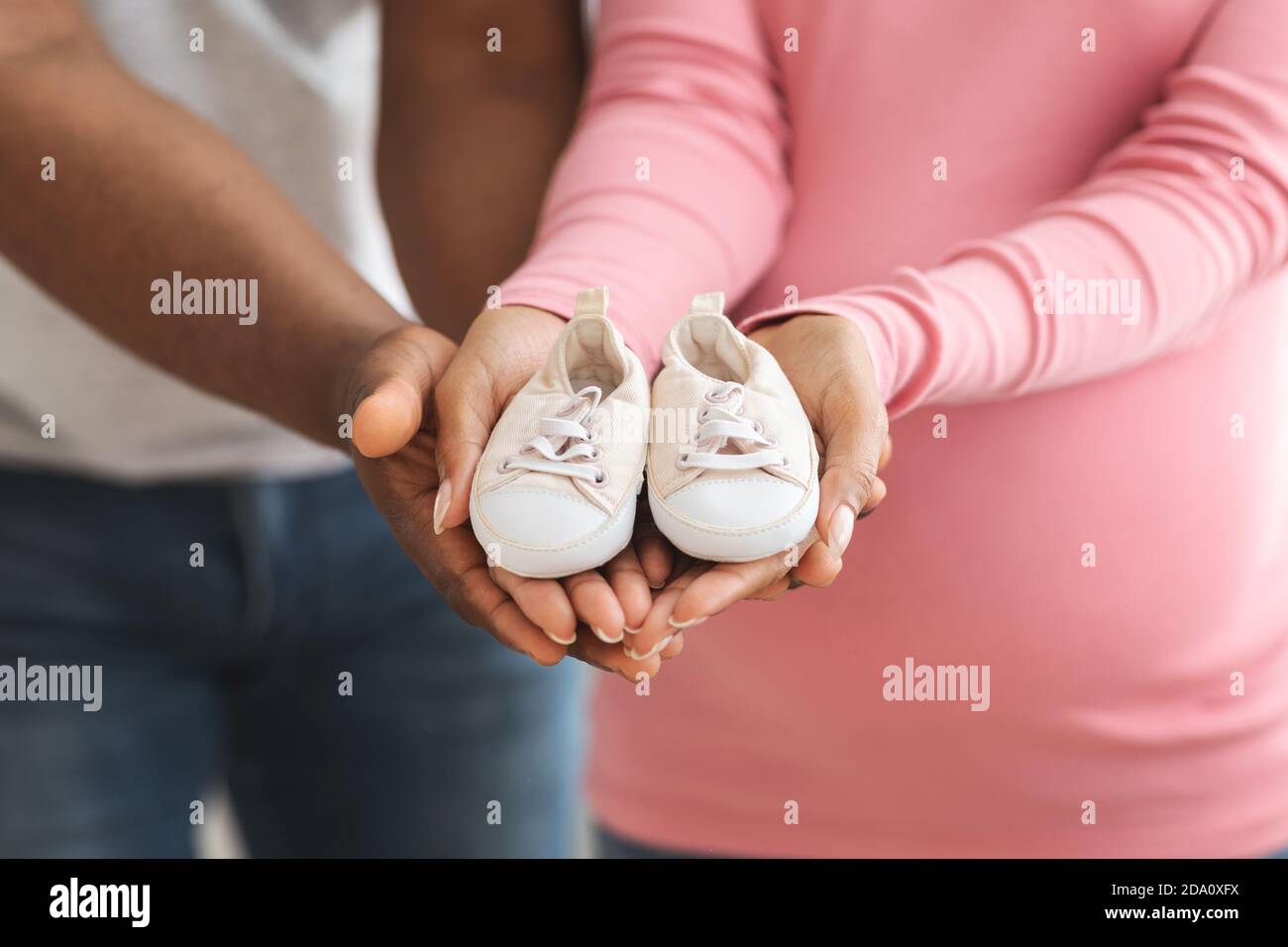 Gros Plan Des Chaussures De Bebe Dans Les Mains De Couple Noir Enceintes Photo Stock Alamy