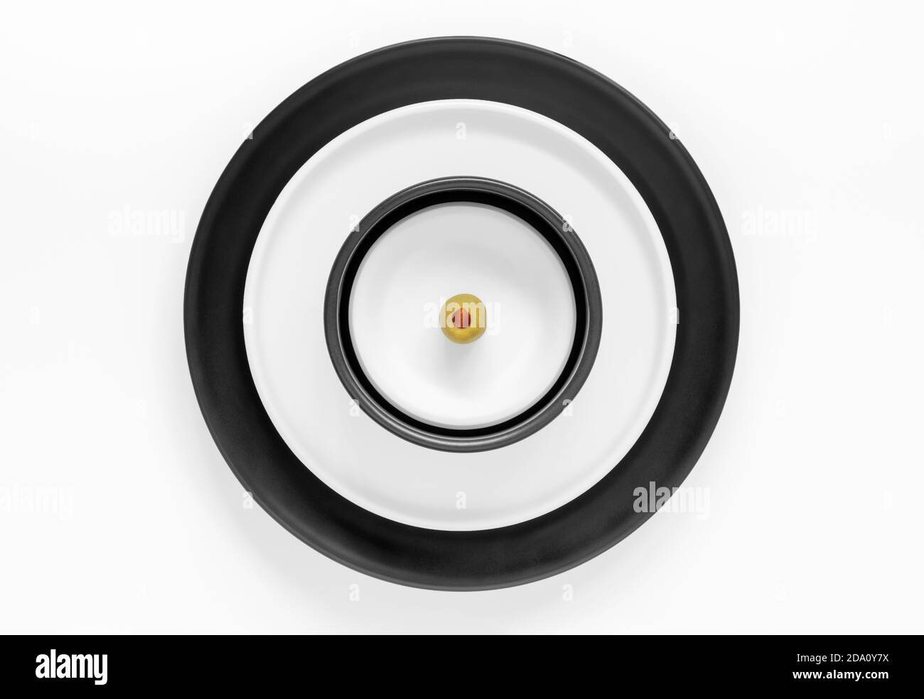 Plaques rondes empilées noires et blanches recouvertes d'une seule plaque olive Banque D'Images