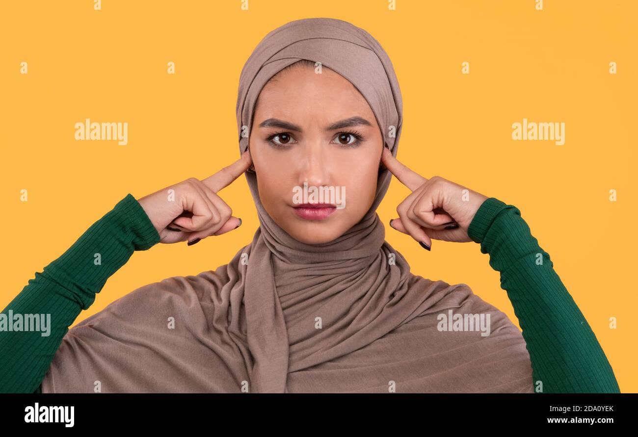 La dame musulmane couvre les oreilles n'écoute pas les autres opinions, fond jaune Banque D'Images