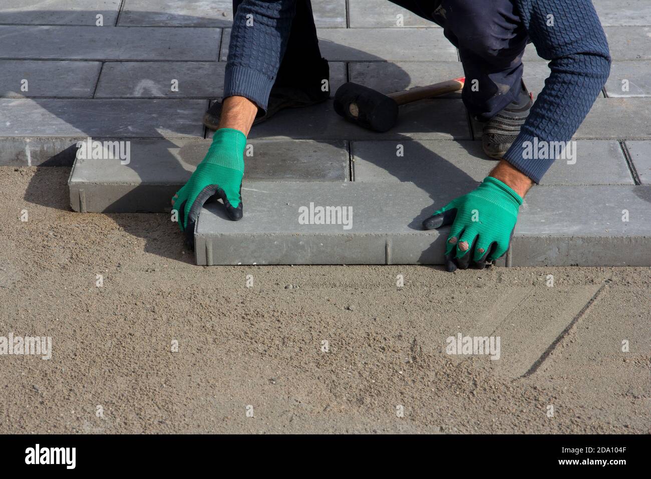 Finisseur sur briques en fonctionnement. Le travailleur pose des carreaux de pavage, construction de pavés de briques. Arrière-plan de l'architecture Banque D'Images