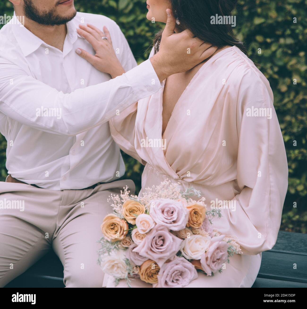 Couple de mariée embrassant sur un banc. Belle mariée avec un bouqet. Banque D'Images Couple de mariée embrassant sur un banc. Belle mariée avec un bouqet. Banque D'Images