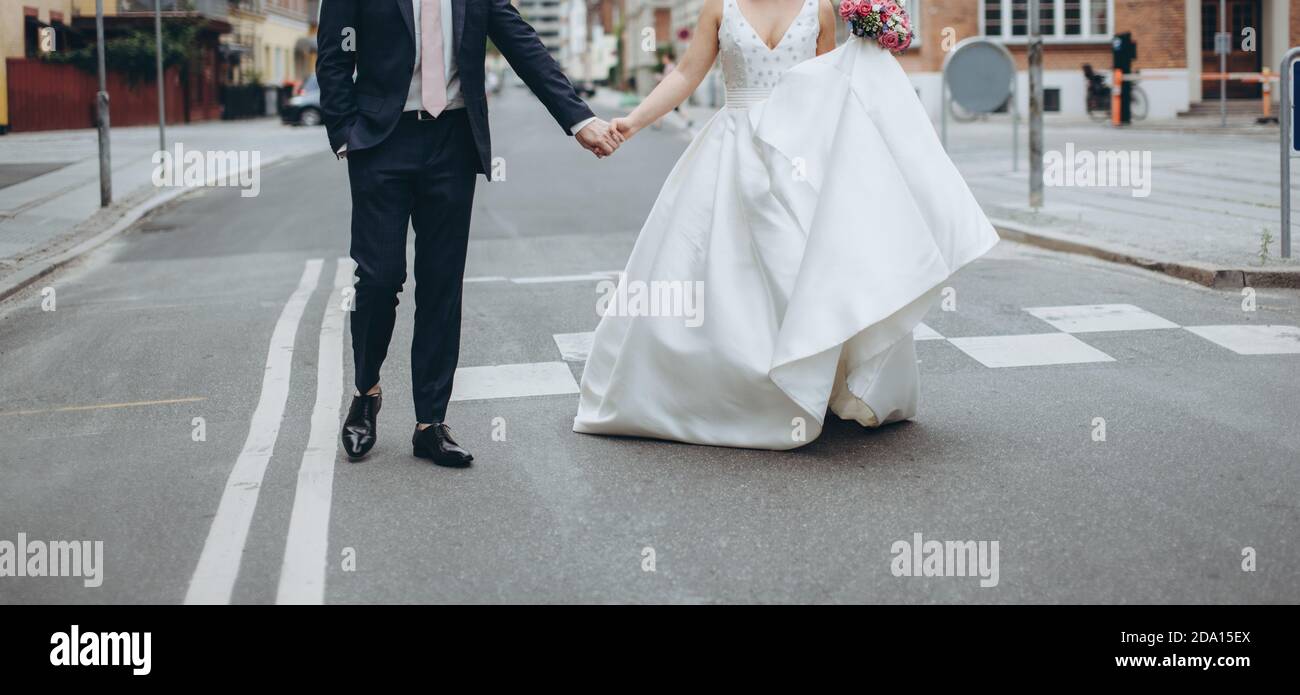 Couple de mariage marchant dans la rue ensemble célébrant le joyeux jour de mariage. Concept d'agence de mariage. Banque D'Images Couple de mariage marchant dans la rue ensemble célébrant le joyeux jour de mariage. Concept d'agence de mariage. Banque D'Images
